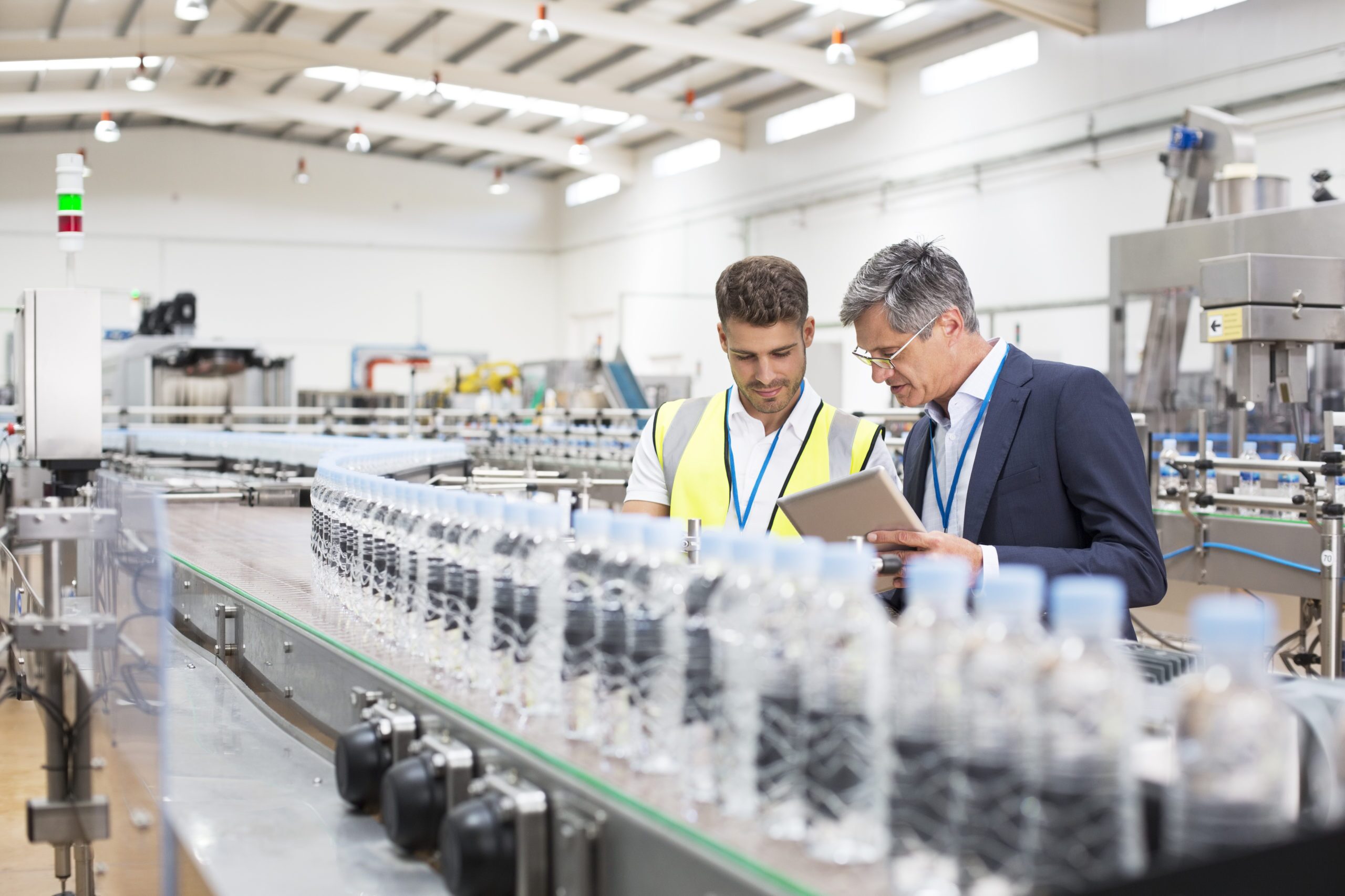 Supervisor and manager watching plastic bottles on conveyor belt