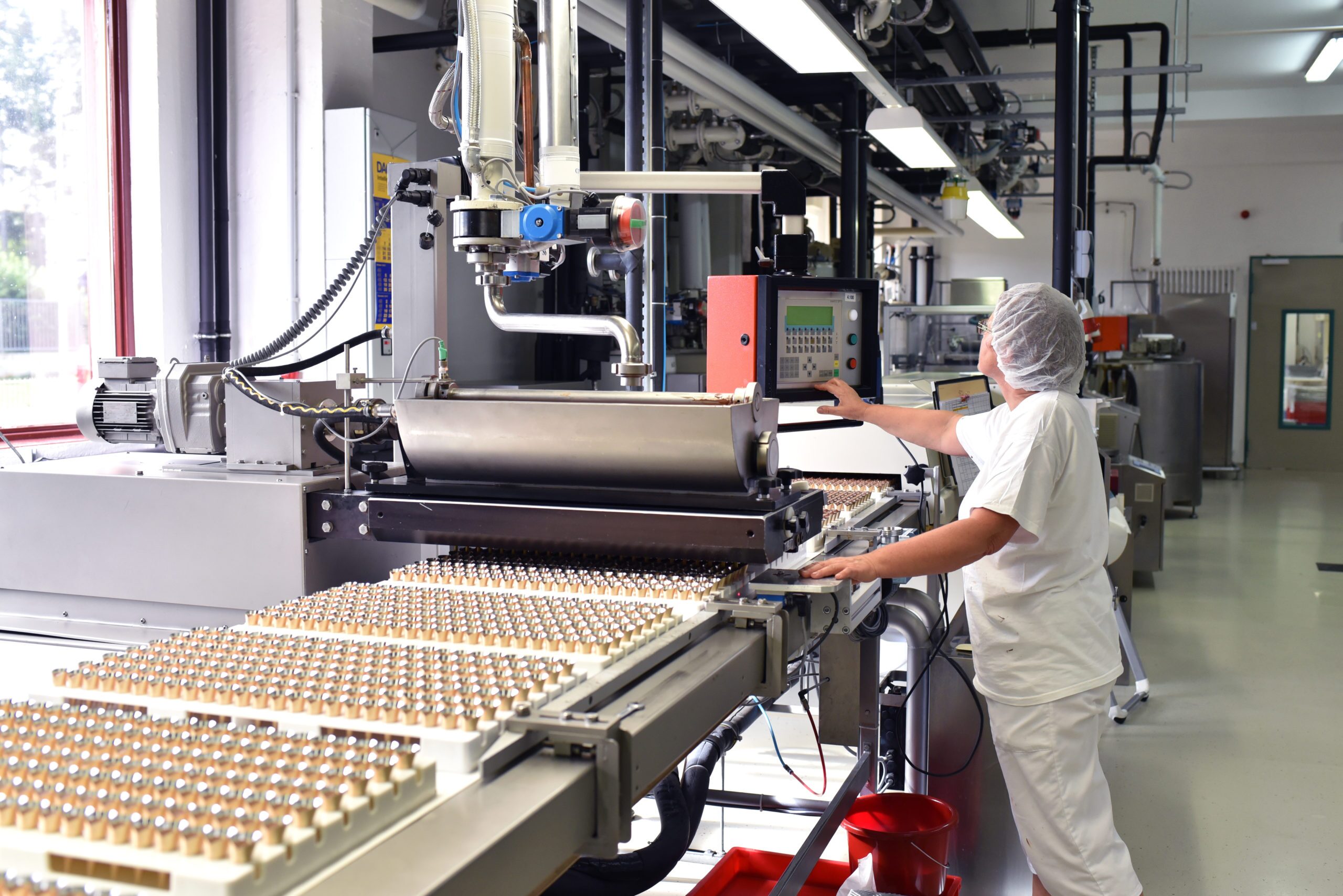 Arbeiterin am Fliessband in der Lebensmittelindustrie - Produktion von Pralinen in einem Werk // Worker on an assembly line in the food industry - Production of pralines in a factory